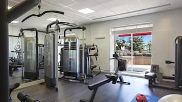 A gym with various exercise machines, a blue mat, and a red exercise ball.