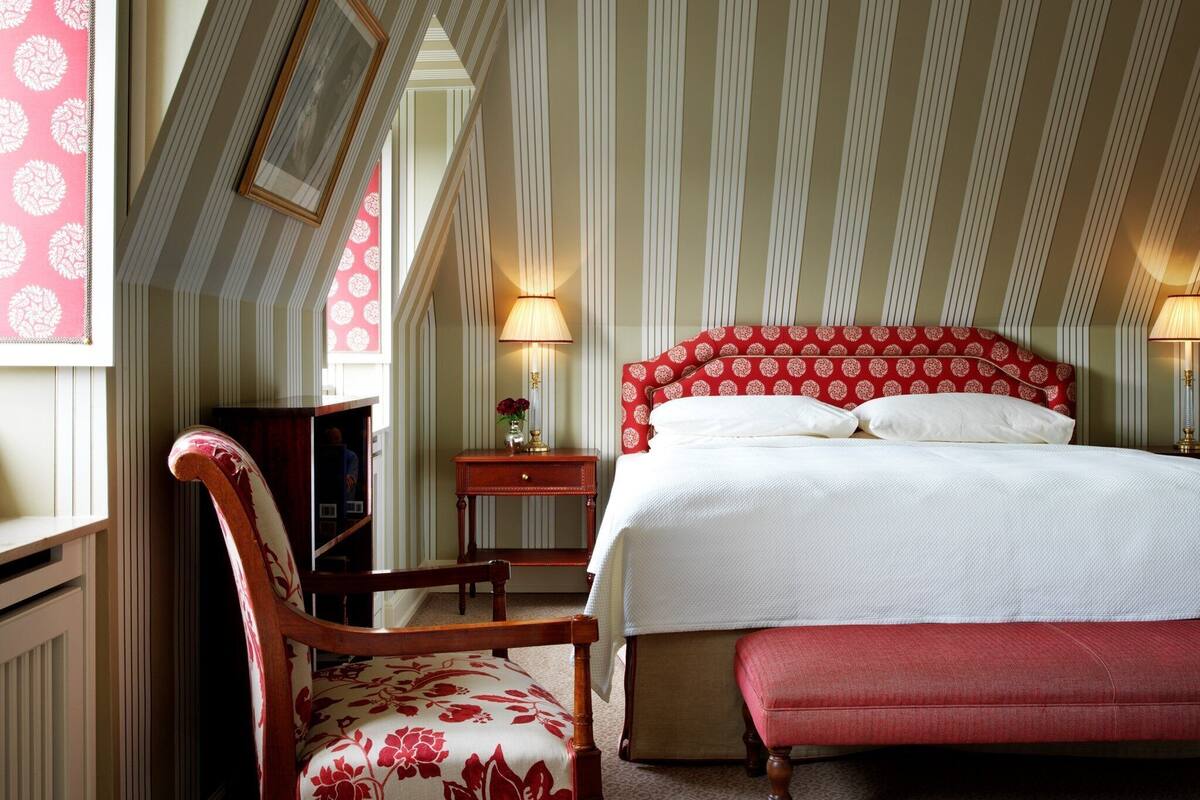 Una habitación de hotel con cama, una silla, una mesita de noche y una lámpara.