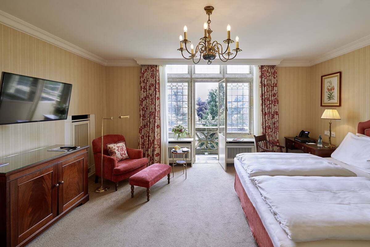 Habitación de hotel con una cama grande, un escritorio con una computadora, un televisor y una silla.