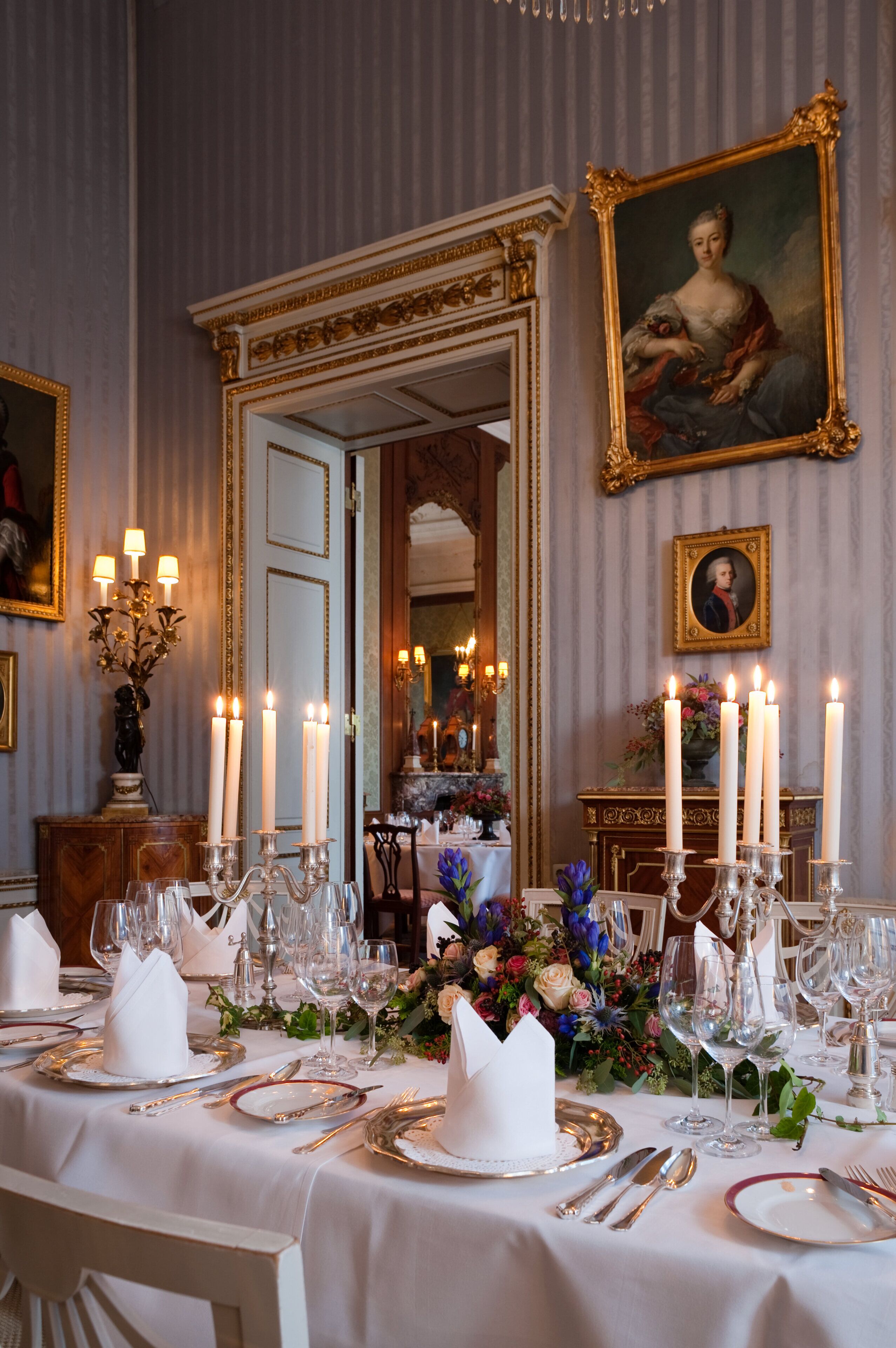 Ein formeller Speisesaal mit gedecktem Tisch, Kerzen und gerahmten Kunstwerken an den Wänden.