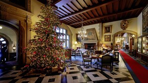 Un vestíbulo amplio con un gran árbol de Navidad, piso a cuadros y arquitectura clásica.