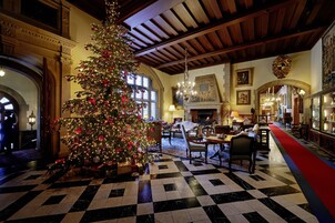 Un vestíbulo amplio con un gran árbol de Navidad, piso a cuadros y arquitectura clásica.