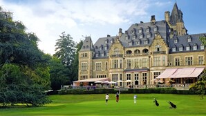 Un edificio grande e histórico con un césped cuidado y zona de estar al aire libre.