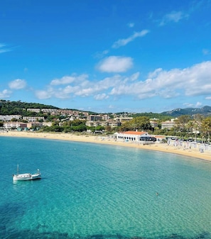 A coastal town with a clear blue sea, a sandy beach, and buildings in the background. - Hostal de la Gavina GL - The Leading Hotels of the World (Castell-Platja d'Aro)