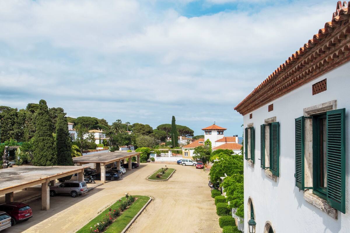 Ein Parkplatz mit Autos, einem überdachten Gang und einem Gebäude mit grünen Fensterläden.