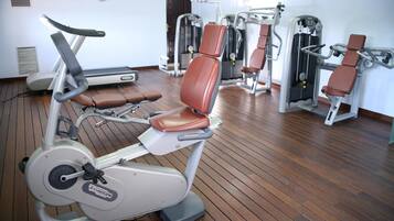 Une salle de sport équipée de machines de cardio, d’appareils de musculation et dotée d’un plancher en bois.