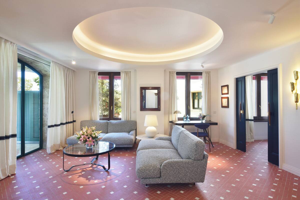Ein modernes Wohnzimmer mit einer runden Deckenleuchte, zwei Sofas, einem Couchtisch und einer Lampe.