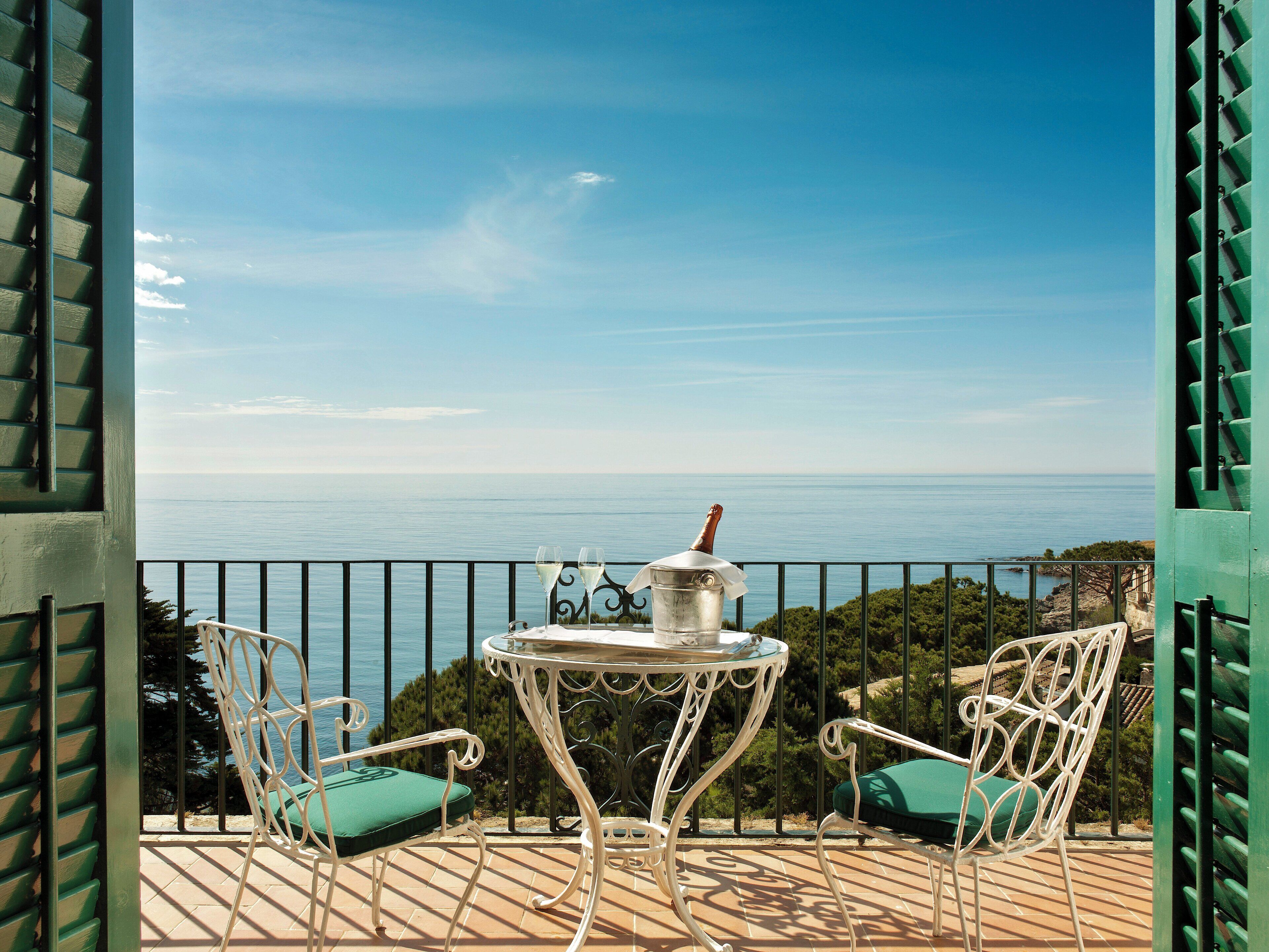 Una terraza con una mesa y sillas, con vista a un cuerpo de agua.