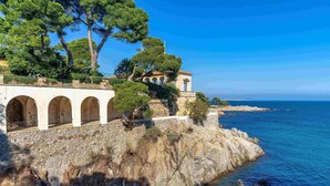 A coastal building with arched windows and a stone facade, overlooking the sea.