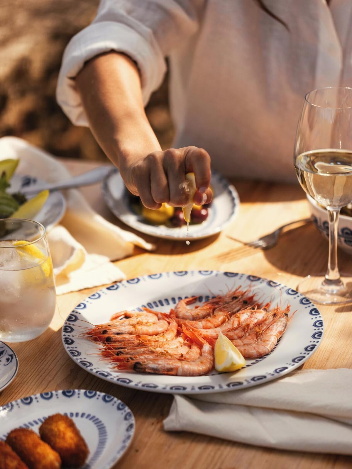 A dining table with plates of food, a glass of water, and a person serving food.