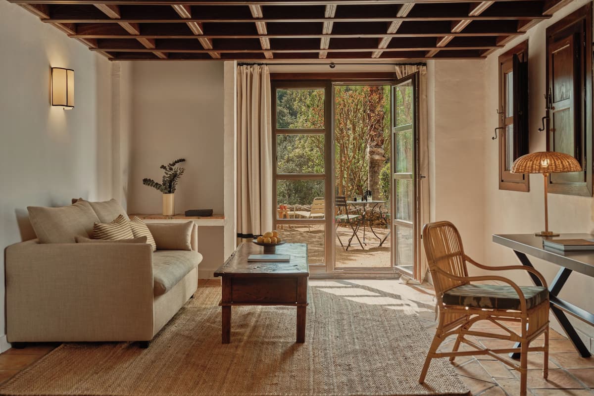 Un salon comprenant un canapé, une table basse, un fauteuil en osier et une table à manger avec une lampe.
