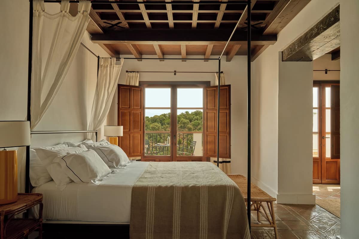 Une chambre à coucher avec un lit à baldaquin, un balcon offrant une vue et un plafond en bois.