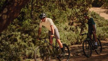 Two cyclists on a dirt path surrounded by greenery.