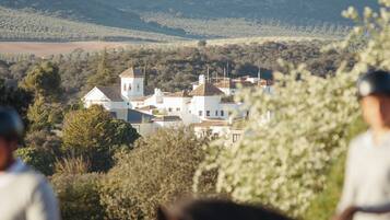 A rural landscape with a white building surrounded by trees and hills.