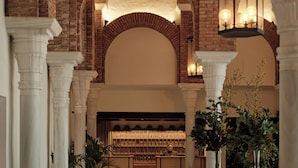 An interior with arched brick ceilings, white columns, and a central wooden counter with a person behind it. - Finca la Bobadilla, Leading Hotels of the World (Loja)