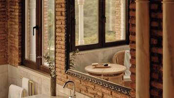 Un baño con lavamanos doble, un espejo grande y vista a un jardín a través de una ventana.