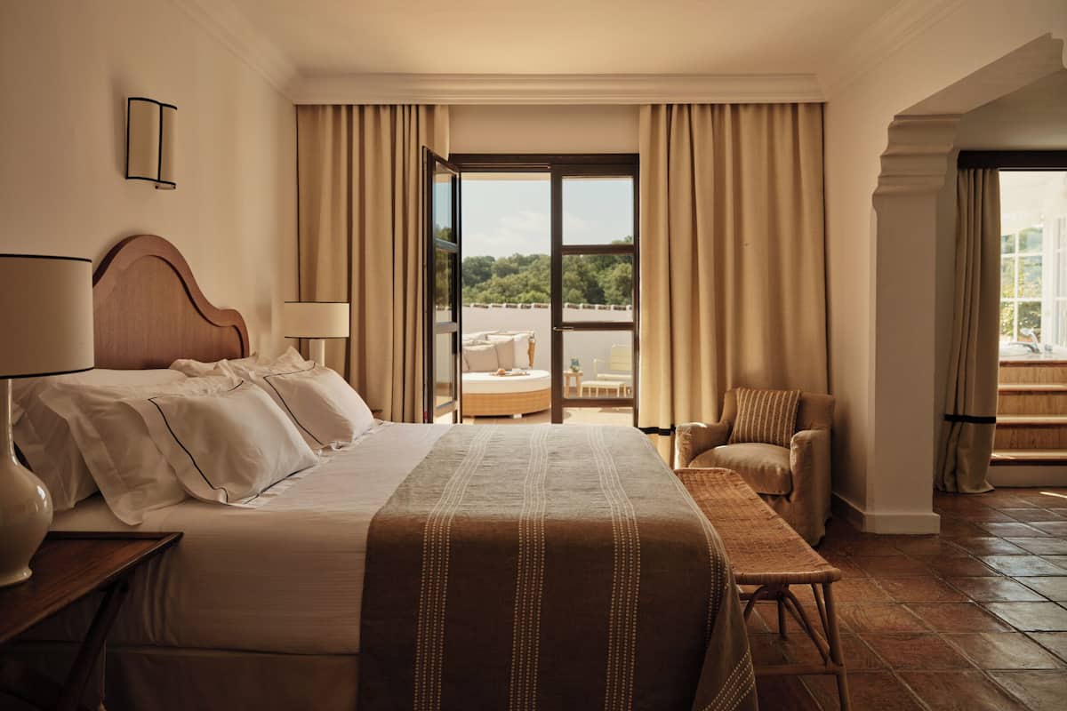 Une chambre d’hôtel avec un grand lit, une chaise, une table et une vue sur l’extérieur.