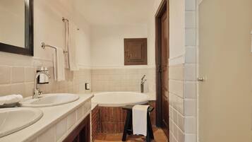 Un baño con dos lavamanos, una bañera, un espejo, un perchero para toallas y una puerta.