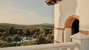 A white building with a brick archway and a view of a pool surrounded by palm trees. - Finca la Bobadilla, Leading Hotels of the World (Loja)