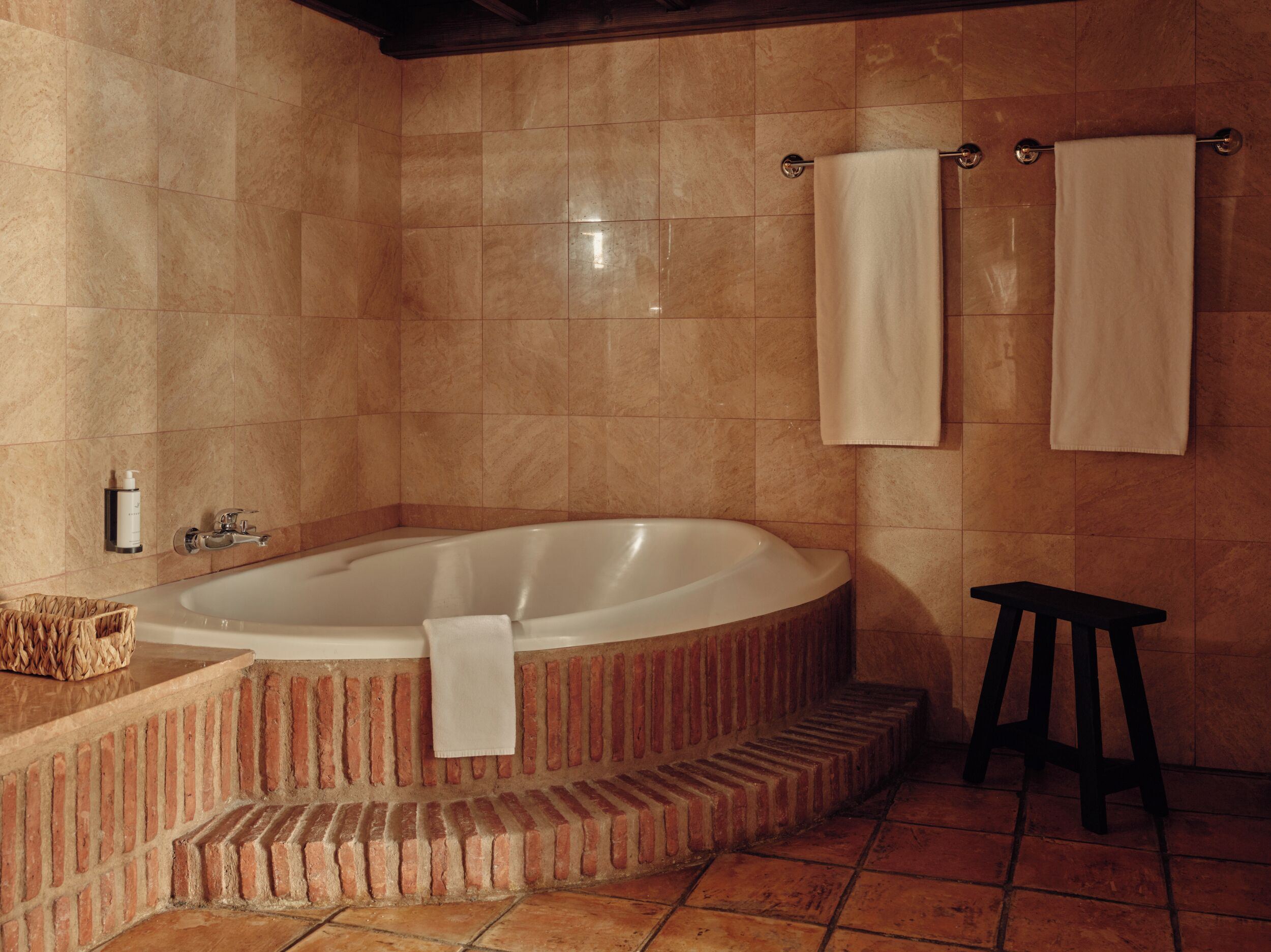 A bathroom with a freestanding bathtub, a towel rack, and a small stool.