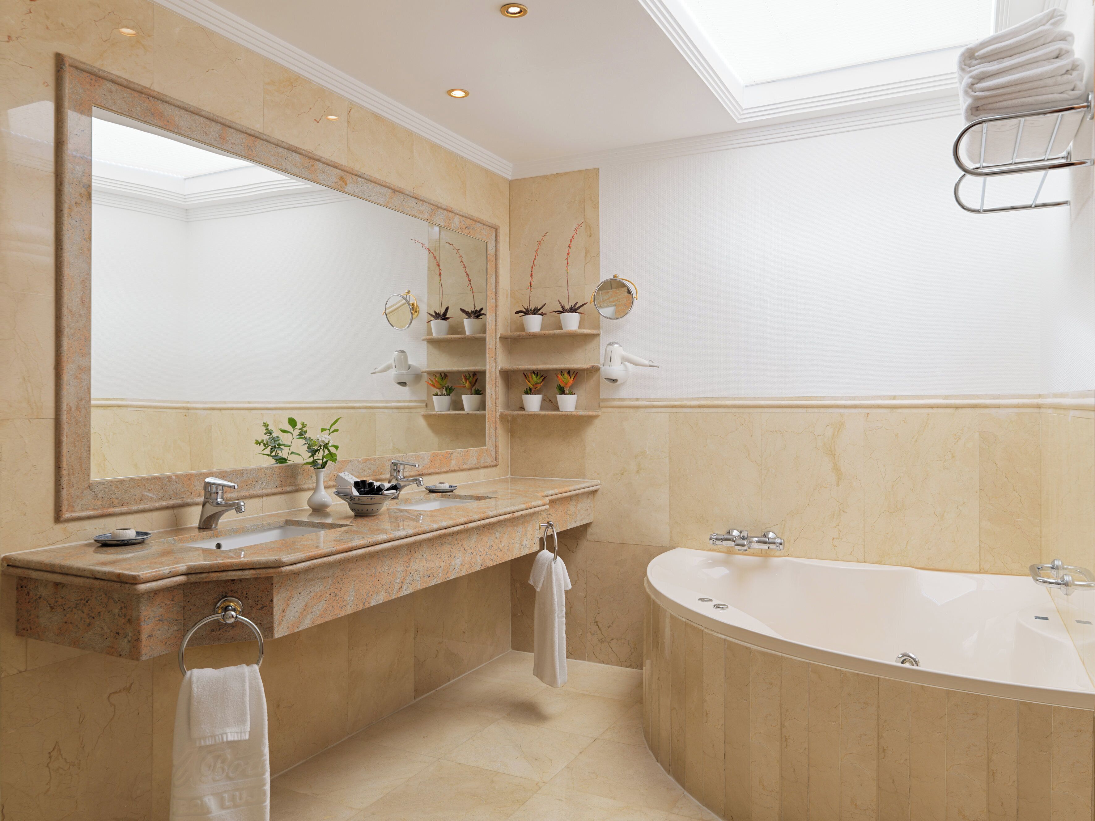 A modern bathroom with a large mirror, a freestanding bathtub, and a vanity with a sink and towel rack.