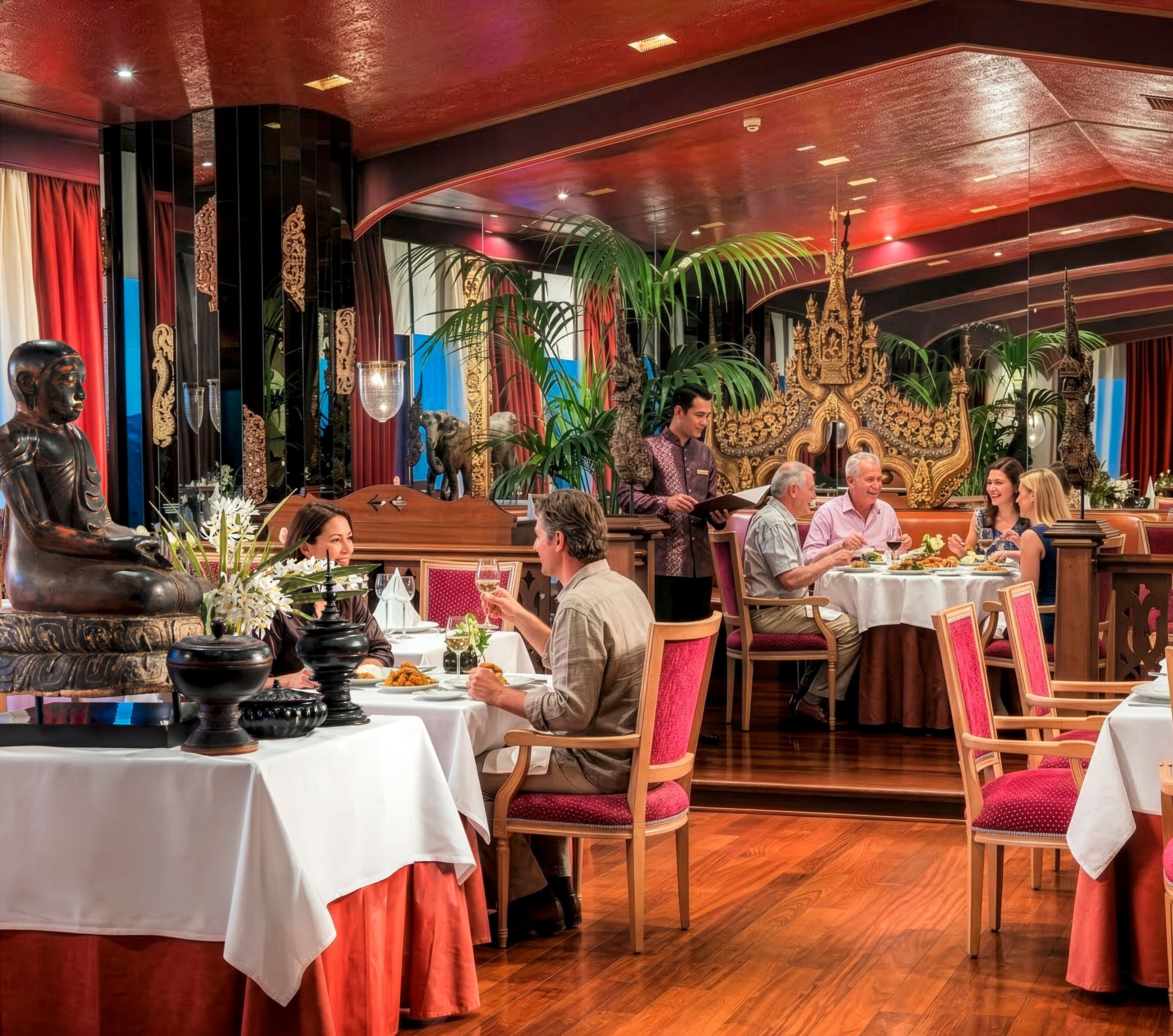 Un restaurante con suelo de madera, mesas con manteles blancos y un camarero atendiendo a los comensales.