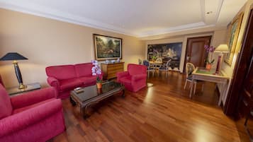 A spacious living room with a red sofa set, a coffee table, and a dining area with a table and chairs.
