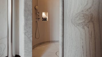 A modern bathroom with a marble floor, a shower area, and a hanging light fixture.