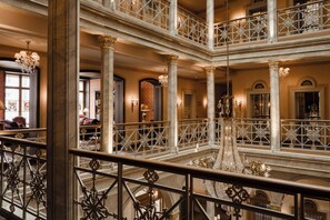 Un atrio de varios niveles con barandillas ornamentales y candelabros.