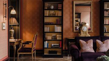 Una habitación con una amplia estantería, una silla, un sofá y un espejo.
