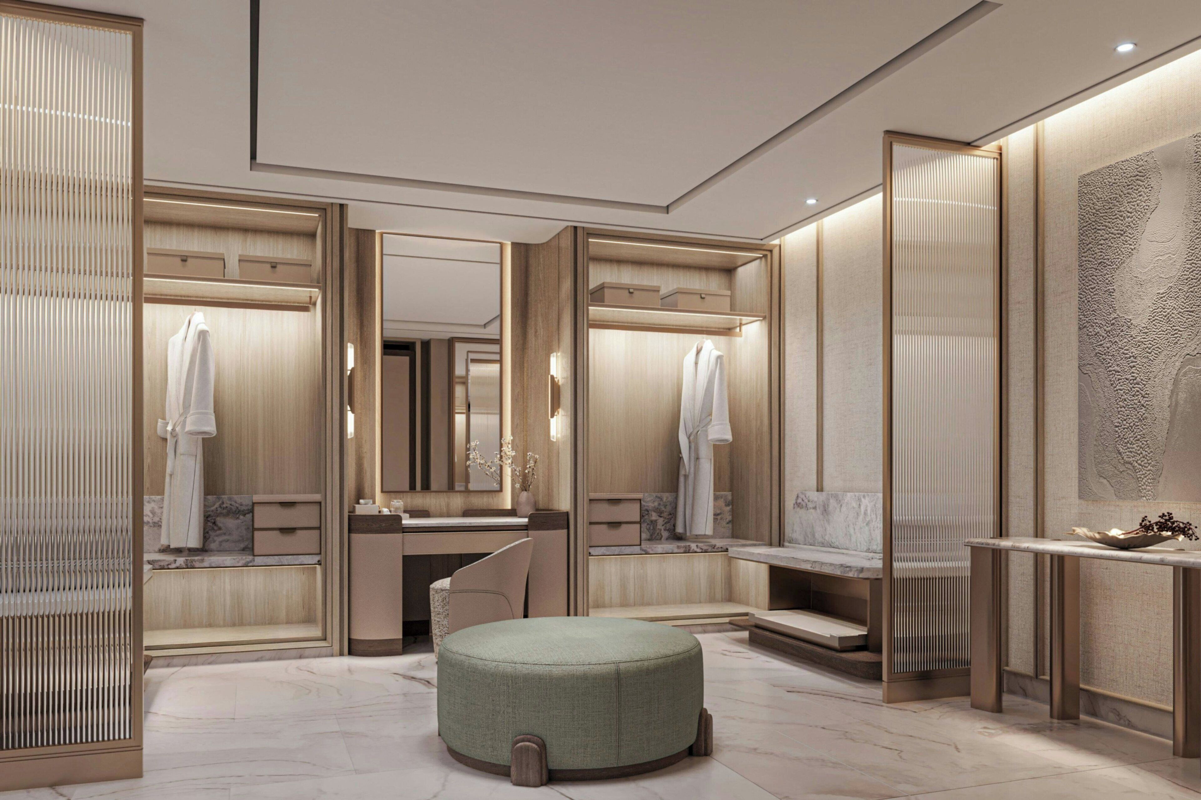 A modern bathroom with a vanity, mirror, and a round ottoman.