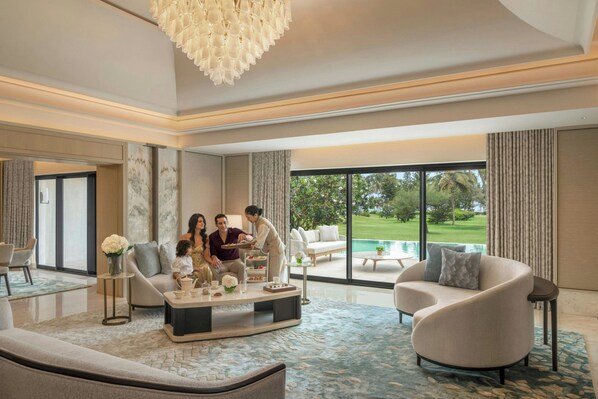 A spacious living room with a large window, a chandelier, and a pool view.