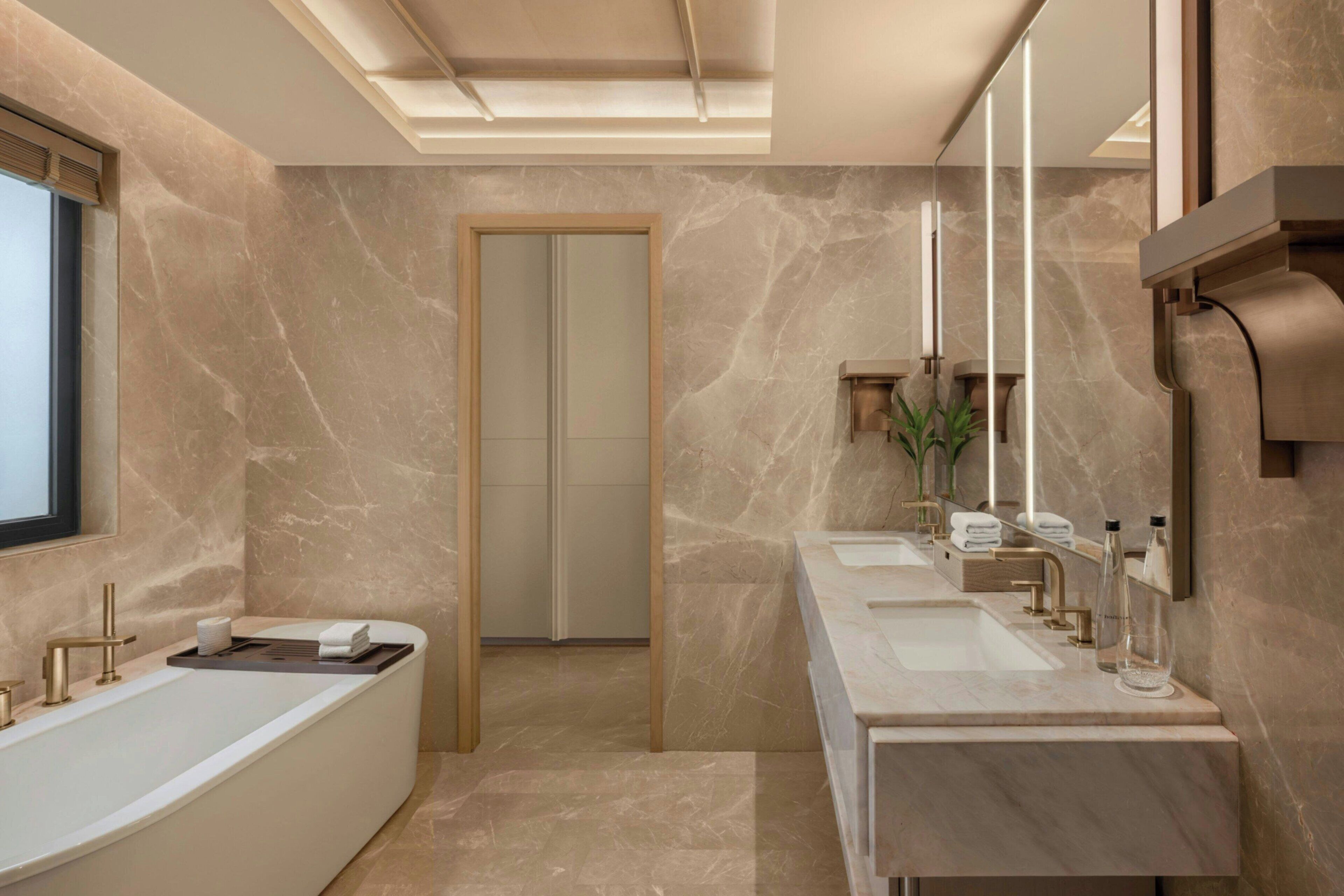A modern bathroom with a freestanding bathtub, two sinks, and a large mirror.