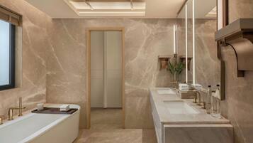 A modern bathroom with a freestanding bathtub, two sinks, and a large mirror.