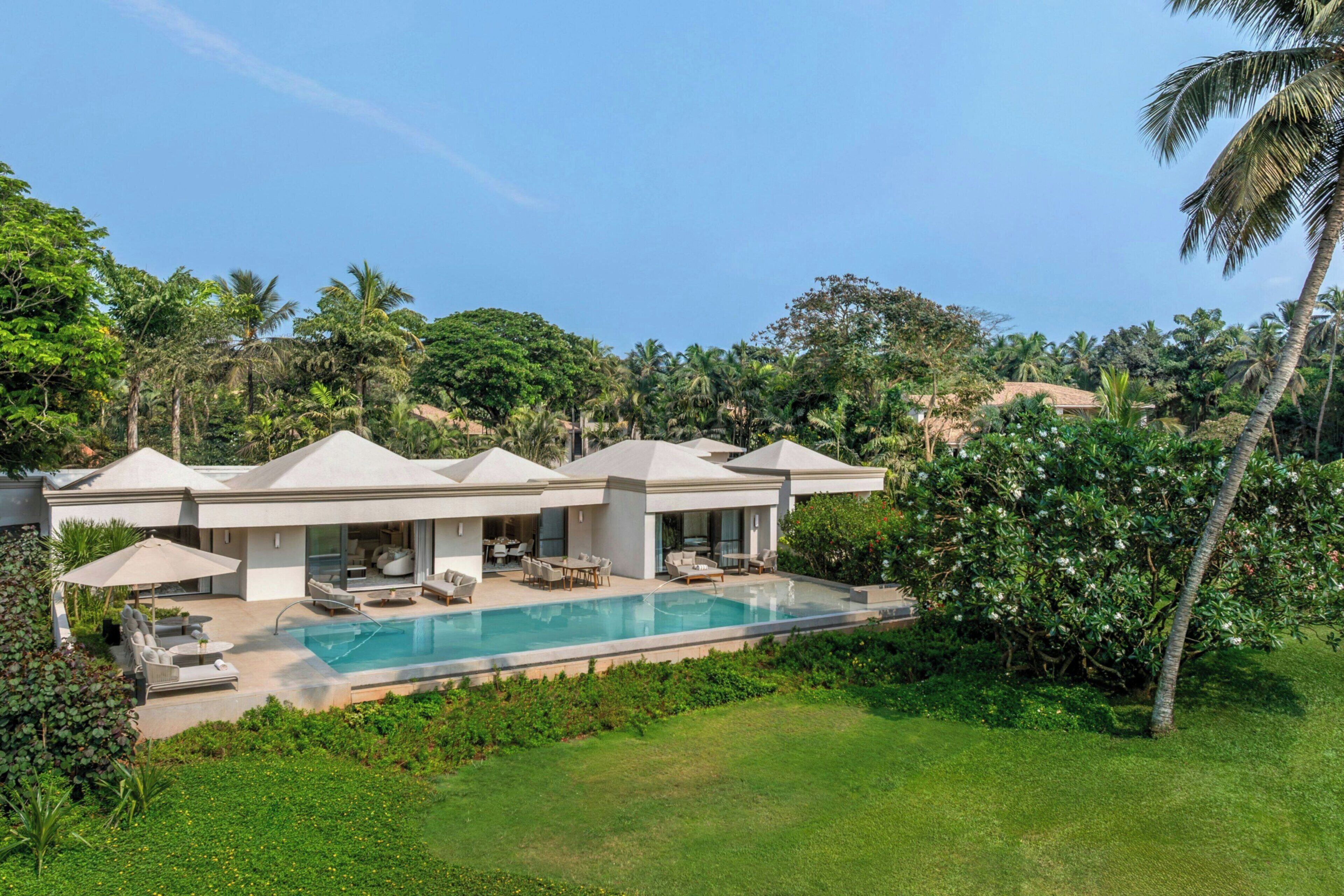 A modern villa with a swimming pool, multiple rooms, and lush greenery.
