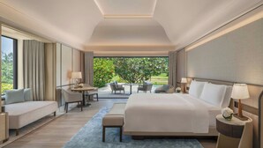 A modern hotel room with a large bed, a seating area with a table, and a view of greenery outside. - The St. Regis Goa Resort (Cavelossim)