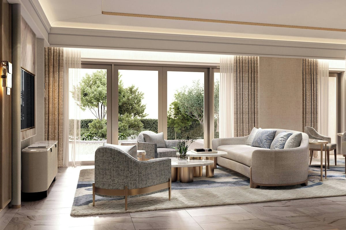 Un salon moderne comprenant un canapé, un fauteuil et une table basse, de grandes fenêtres offrant une vue sur la verdure et un téléviseur à écran plat.