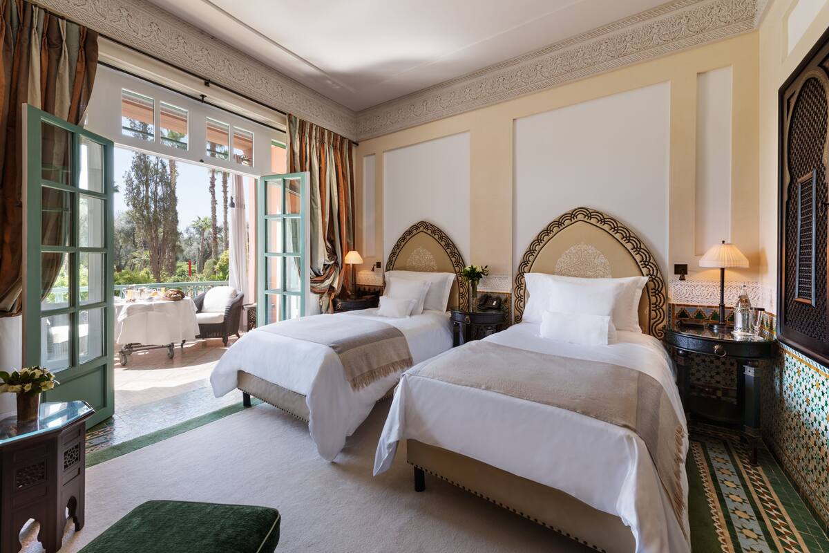 Una camera d'albergo con due letti, vista sull'esterno e un balcone.