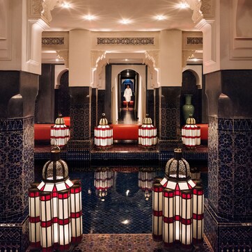 A luxurious lobby with a central red carpet, ornate columns, and decorative lanterns.
