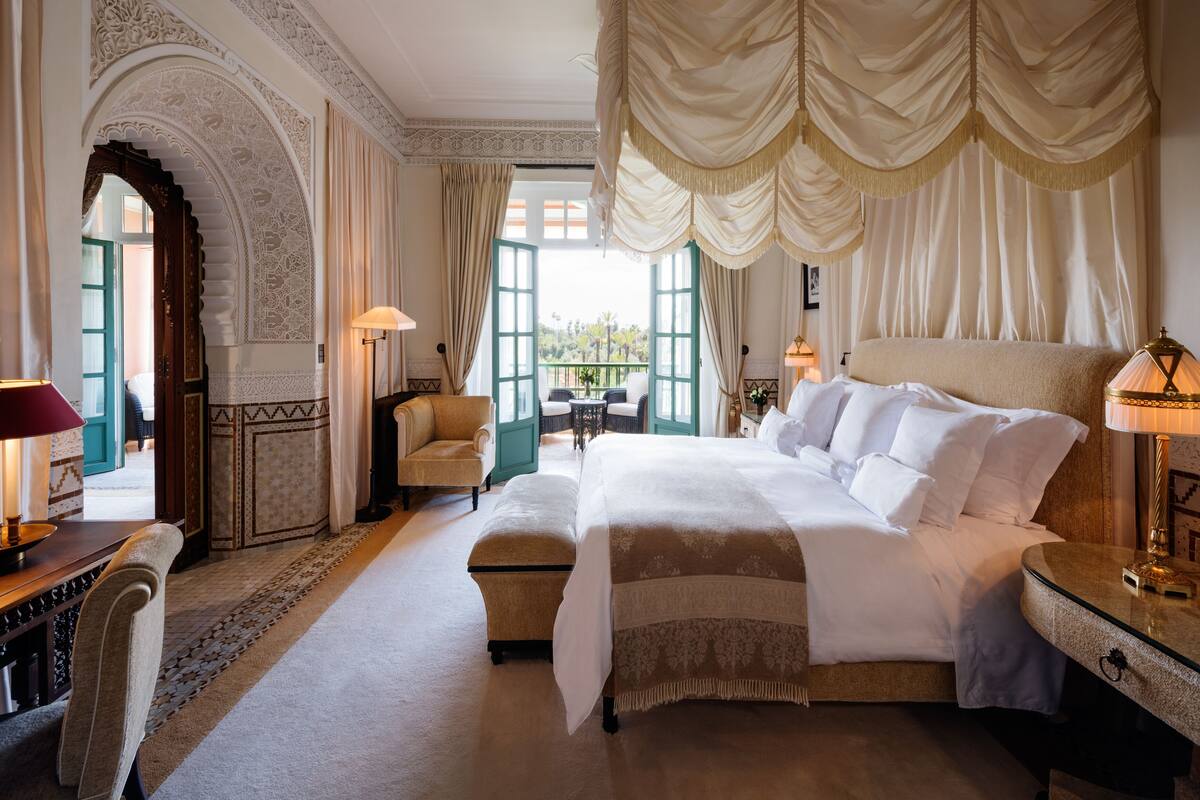 Un'ampia camera da letto con un letto grande, un angolo relax con una poltrona e un tavolino, e vista da una finestra.