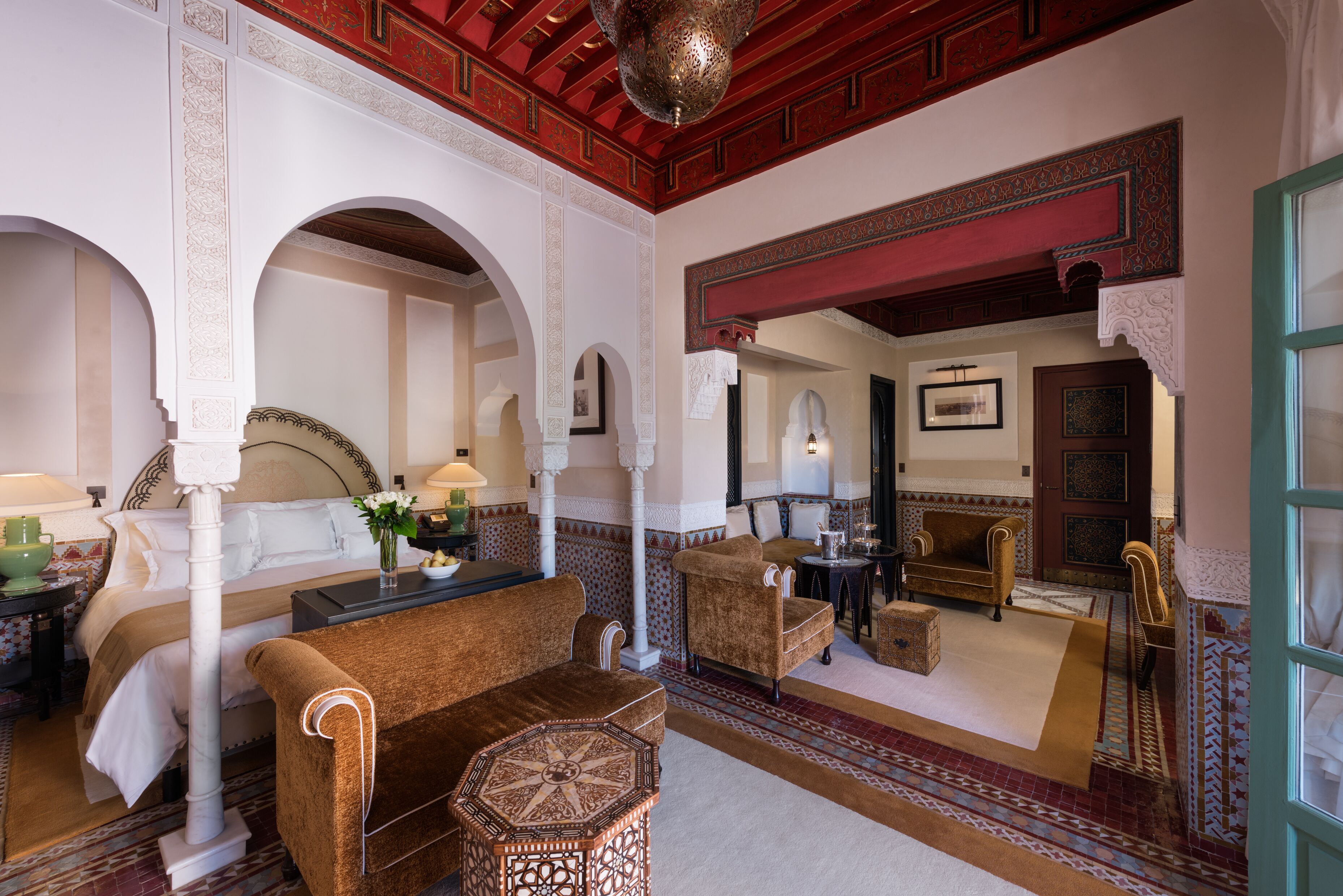 A traditional room with a bed, seating area, and a decorative mirror.