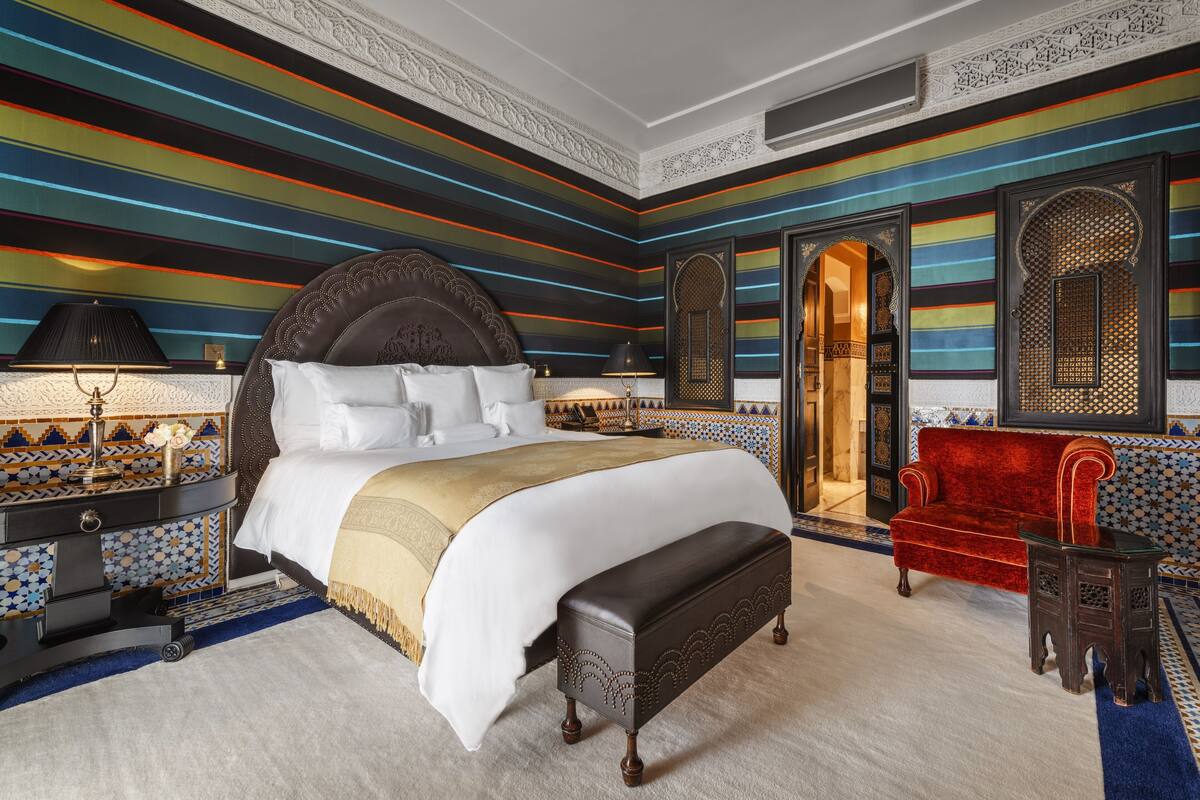 Un'ampia camera da letto con un letto grande, un divano in velluto rosso e decorazioni elaborate alle pareti.