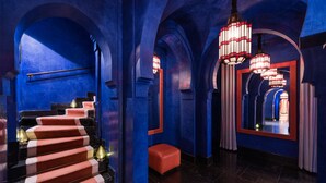 A grand hallway with a red and white striped staircase, blue walls, and multiple arches.