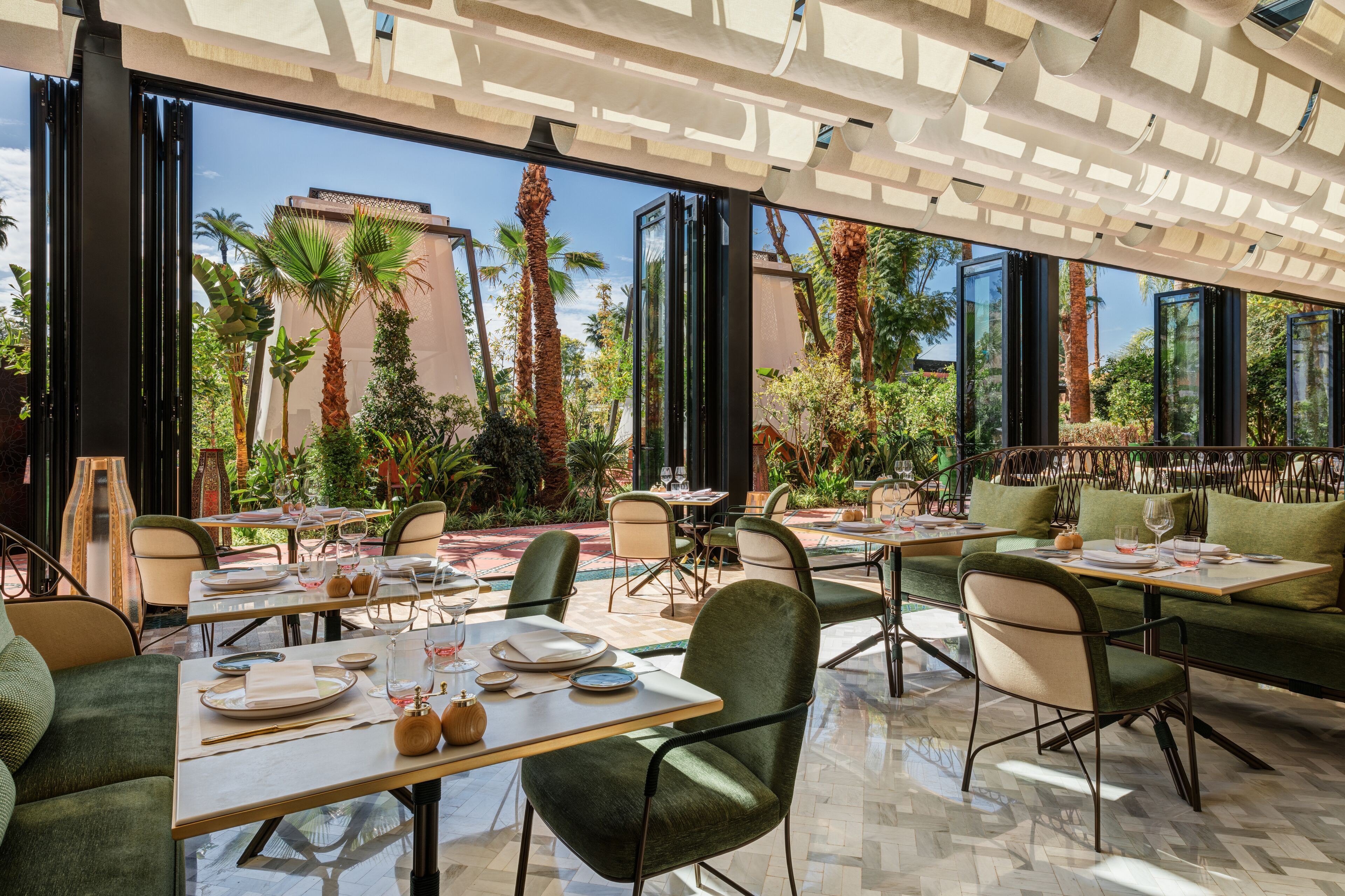 A restaurant with outdoor seating, large windows, and a view of palm trees and a building.
