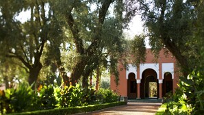 A pathway leading to a building with arches and surrounded by lush greenery.
