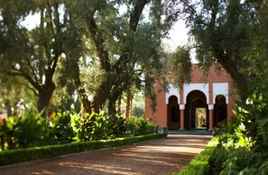 A pathway leading to a building with arches and surrounded by lush greenery.