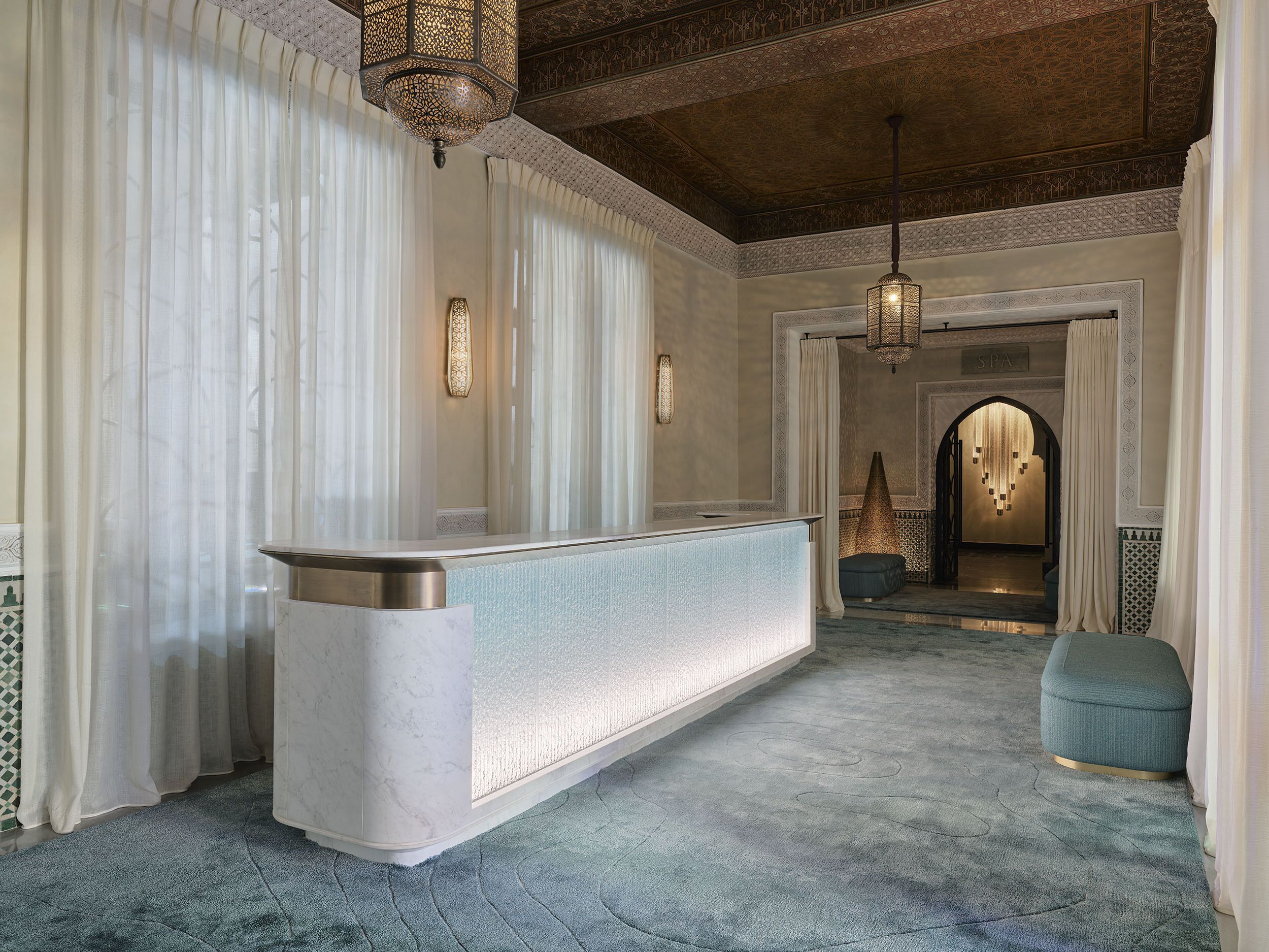 A reception area with a marble counter, patterned curtains, and a carpeted floor.