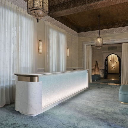 A reception area with a marble counter, patterned curtains, and a carpeted floor.