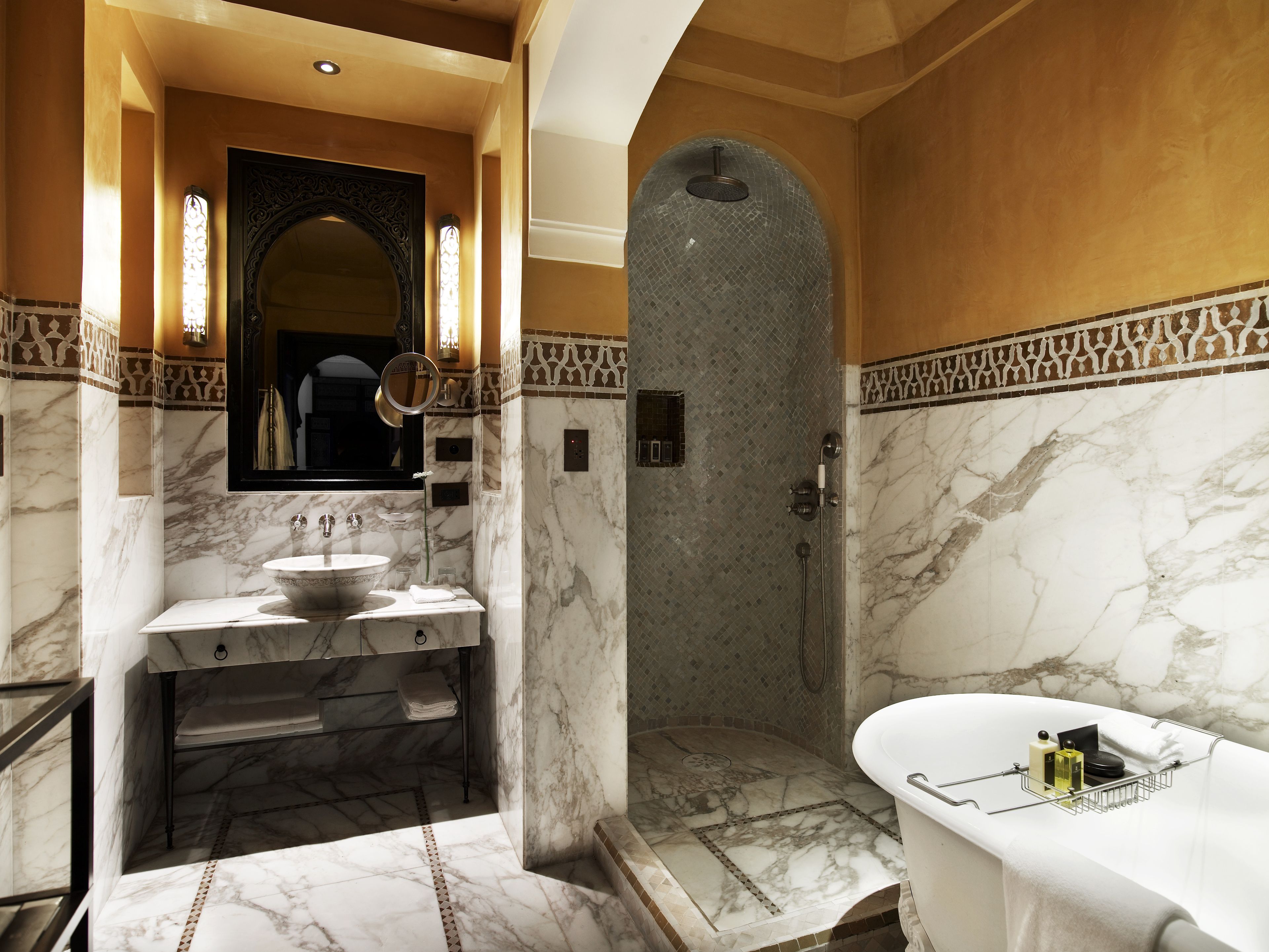 Une salle de bain avec un lavabo en marbre, un grand miroir, une douche et une baignoire.
