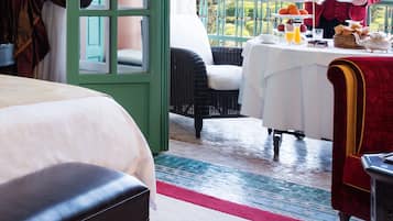 Une chambre d’hôtel avec un balcon, un lit, une table à manger où le petit-déjeuner est servi, et une vue sur une tour.